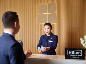 mężczyzna i kobieta stojący przy biurku w obiekcie Hilton Garden Inn Anshan w Anshan