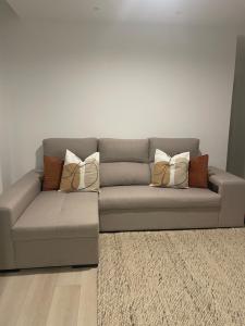 ein graues Sofa mit Kissen darauf im Wohnzimmer in der Unterkunft Modern Spacious Apartment in Entroncamento