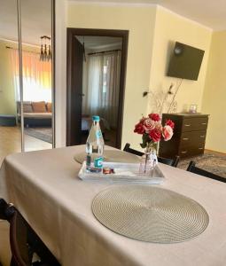 a table with a bottle of water and flowers on it at Apartament Terra II in Floreşti