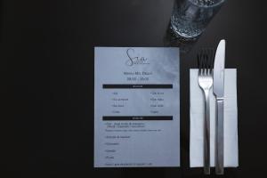 una mesa cubierta con un menú y un tenedor y un cuchillo en Sia Boutique Aparthotel, en Sibiu