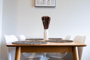 a table with white chairs and a vase of sticks at Luxury Apartment West Hollywood in Los Angeles