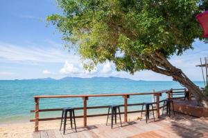 a table and chairs under a tree on the beach at Adarin Beach Resort in Mae Nam