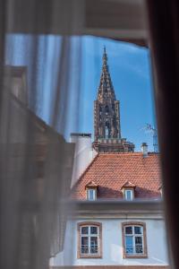 uma torre de relógio no topo de um edifício com telhado em Chez Françoise - Marché de Noël 3min à pied - Vue Cathédrale em Estrasburgo