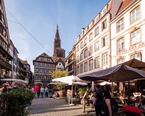 uma rua da cidade com edifícios e pessoas sentadas a mesas em Chez Françoise - Marché de Noël 3min à pied - Vue Cathédrale em Estrasburgo