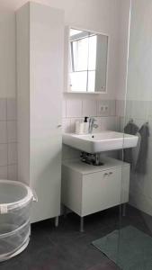 Baño blanco con lavabo y espejo en Moderne Neue 2 Zimmer Wohnung, en Uetersen