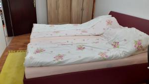 Una cama con sábanas blancas con flores rosas. en Berta Apartman, en Senta