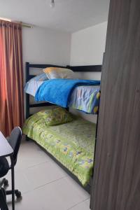 a bedroom with two bunk beds and a chair at Apartamento hogareño in Pereira