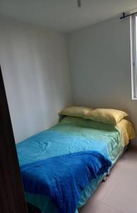 a bedroom with a bed with blue sheets and a window at Apartamento hogareño in Pereira