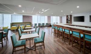 a dining room with tables and chairs and a bar at Hampton Inn By Hilton Hamilton in Hamilton