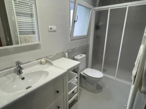 La salle de bains blanche est pourvue d'un lavabo et de toilettes. dans l'établissement Casa da Baltasara, à Trives