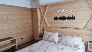 1 dormitorio con 1 cama con pared de madera en Hotel Villa Gaia, en Cortina dʼAmpezzo