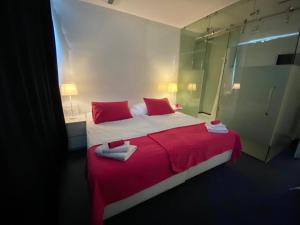 - une chambre avec un grand lit et des oreillers rouges dans l'établissement Business Hotel Wiesbaden PRIME, à Wiesbaden