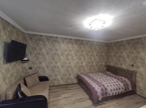 a bedroom with a bed and a couch and a tv at gabro in Mtskheta