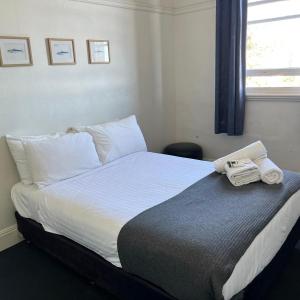 een slaapkamer met een bed met een telefoon erop bij Beachside Budget Rooms in Kiama