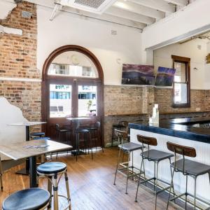 een bar in een restaurant met tafels en stoelen bij Beachside Budget Rooms in Kiama