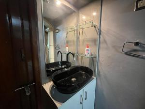 baño con lavabo negro y espejo en SAN HOME STAY, en Mysore