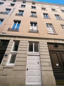 un edificio alto con una puerta y ventanas blancas en Bellecour Pavillon, en Lyon