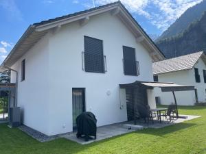 ein weißes Haus mit einem Tisch und Stühlen in der Unterkunft Villa Sofie in Meiringen