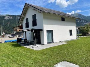 ein weißes Haus mit Rasen davor in der Unterkunft Villa Sofie in Meiringen