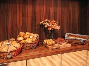 a table with baskets of bread and a vase of flowers at ibis Styles Wałbrzych in Wałbrzych