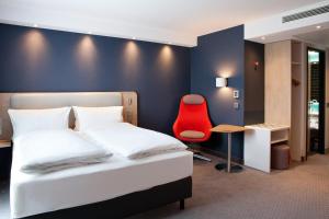 ein Schlafzimmer mit einem Bett und einem roten Stuhl in der Unterkunft Holiday Inn Express Fürth, an IHG Hotel in Fürth