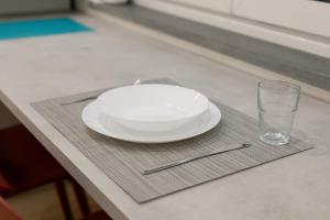 a white plate and a glass on a table at Maison Nona in Torre del Greco