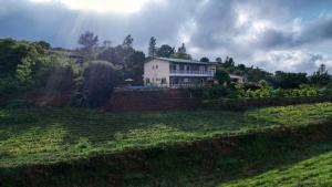 ein Haus auf einem Hügel mit einem Feld in der Unterkunft Elsewhere Villa by Hill Staytion in Mahabaleshwar