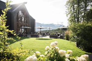 ADLER Lodge RITTEN في سوبرابولسانو: حديقة فيها كراسي ومظلات على عشب