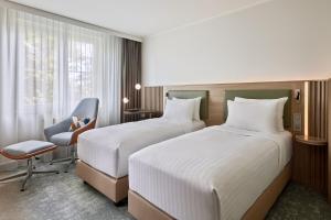 une chambre d'hôtel avec deux lits et une chaise dans l'établissement Courtyard by Marriott Dortmund, à Dortmund