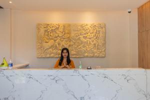 une femme assise au comptoir dans une pièce avec une peinture dans l'établissement The Baliem Hotel, à Jimbaran