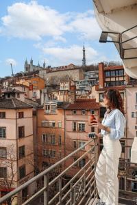 une femme debout sur un balcon en regardant son téléphone portable dans l'établissement Collège Hôtel, à Lyon