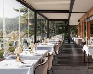 ein Restaurant mit weißen Tischen und Stühlen und großen Fenstern in der Unterkunft Les Mazots du Clos in Villars-sur-Ollon