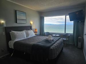 a hotel room with a bed with a view of the ocean at Tui Oaks Motel in Taupo