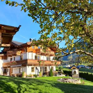 une maison avec une pelouse verte devant elle dans l'établissement Ferienbauernhof Stallhäusl, à Fieberbrunn