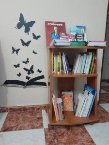 uma estante de livros com livros e borboletas na parede em Disfruta de un barrio tranquilo em Alcalá de Guadaira