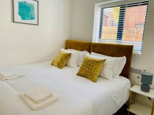 uma cama com lençóis e almofadas brancos e uma janela em Ten - Central Apartment - Contractors Professionals em Gloucester