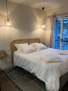 1 dormitorio con 1 cama con sábanas blancas y ventana en Appartement vue sur le port - Chez Carlu, en Bonifacio