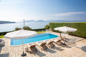 een zwembad met stoelen en parasols en het water bij Ionian Calm Villas in Vasiliki