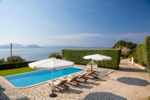 een zwembad met stoelen en parasols en de oceaan bij Ionian Calm Villas in Vasiliki