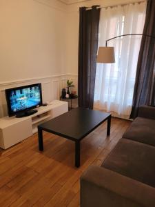 a living room with a coffee table and a television at L'appartement Idéal 4 voyageurs in Boulogne-Billancourt