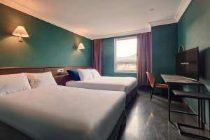 a hotel room with two beds and a desk and a window at Kolon Hotel in Gyeongju