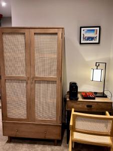 une armoire en bois à côté d'un bureau avec une lampe dans l'établissement Kyoto Rooms Winchester, à Winchester