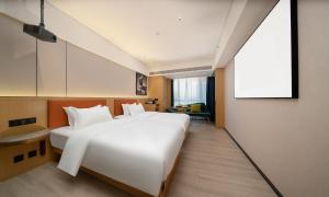 una camera d'albergo con un grande letto bianco e uno schermo per proiezioni di Guangzhou Baiyun Airport COCO Hotel a Huadu