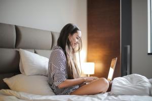 una mujer sentada en una cama mirando un portátil en The Yarn, en Horgen