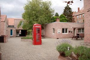 an old red phone booth in a courtyard at Room in Apartment - Condo Gardens Leuven - Student Flat Semiduplex in Leuven