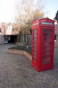 a red phone booth sitting on a brick street at Room in Apartment - Condo Gardens Leuven - Student Flat Semiduplex in Leuven