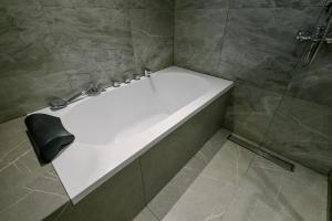 een badkamer met een douche en een wit bad bij Ardenhills Suites in Manilla