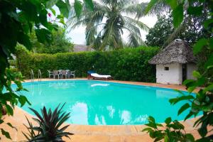 - une piscine dans une cour avec toit de chaume dans l'établissement Villas Dora and Holly, à Diani Beach