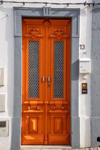 una puerta naranja en el lateral de un edificio en Tavira Nomad Guesthouse, en Tavira