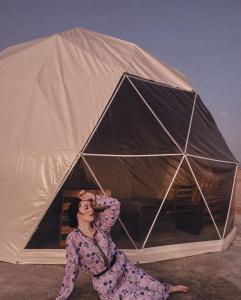 een vrouw zit voor een tent bij Golden Desert Camp Al Wasil in Al Wāşil